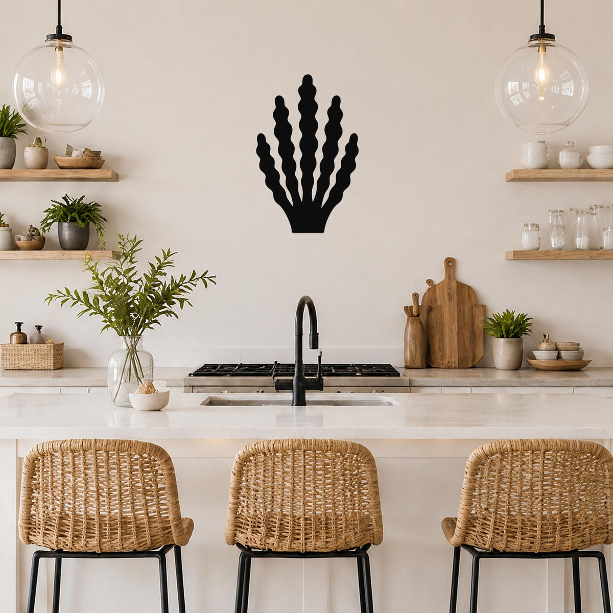 Black metal kelp wall art with wavy frond cutouts, mounted on a kitchen wall above a counter between two glass pendant lights.