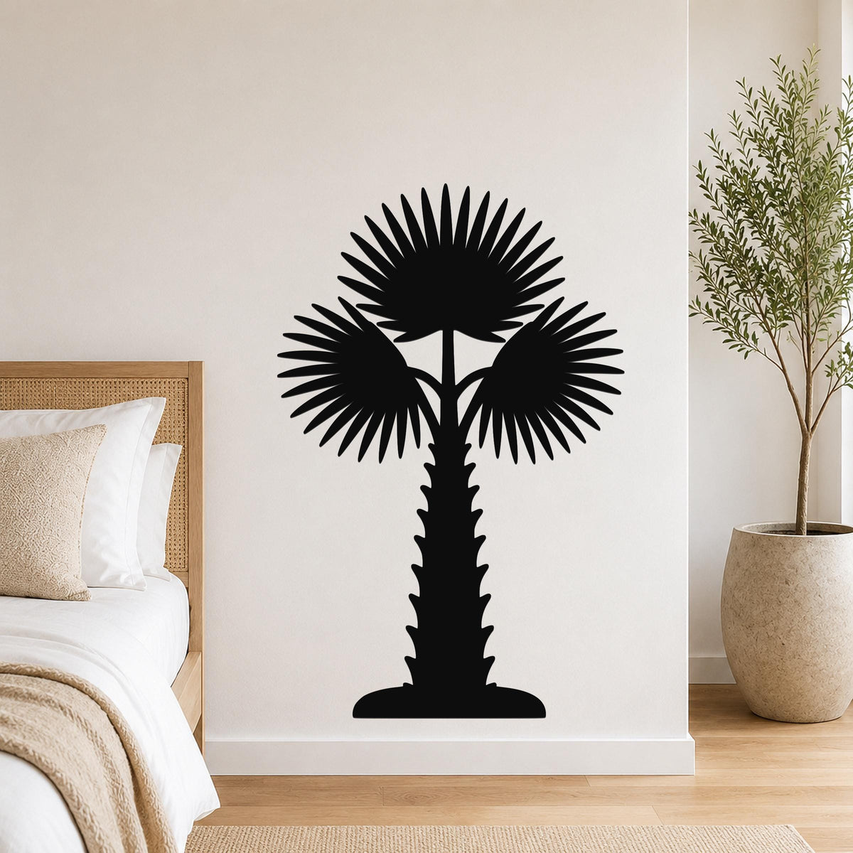 Black metal palm tree wall art with fan-shaped fronds and a textured trunk, mounted on a wall above a bed in a modern bedroom.