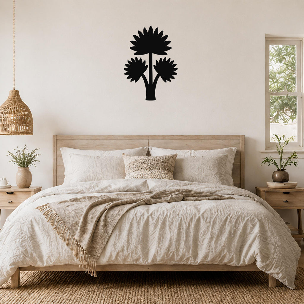 Black metal wall art in a fan palm tree silhouette with three flower-like shapes, mounted above a wooden bed in a neutral bedroom.