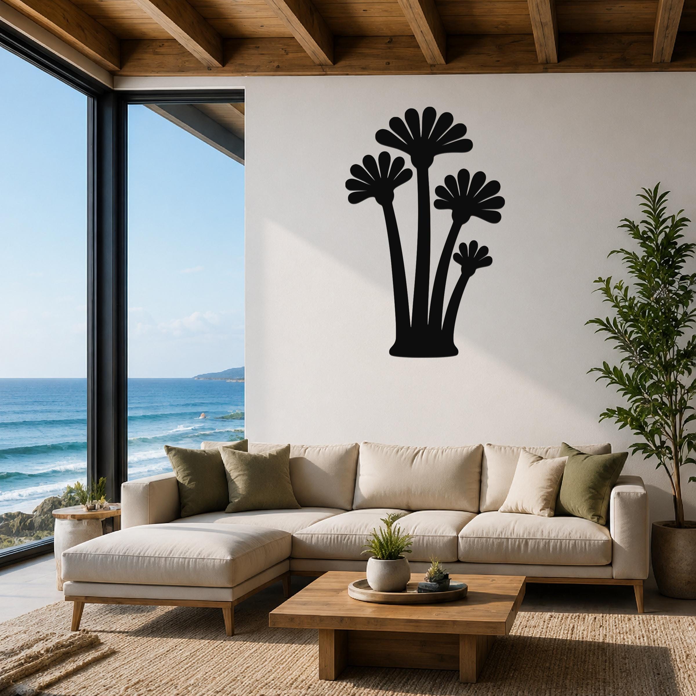 Black metal wall art featuring a fan palm tree silhouette, mounted on a living room wall above a beige sectional sofa.