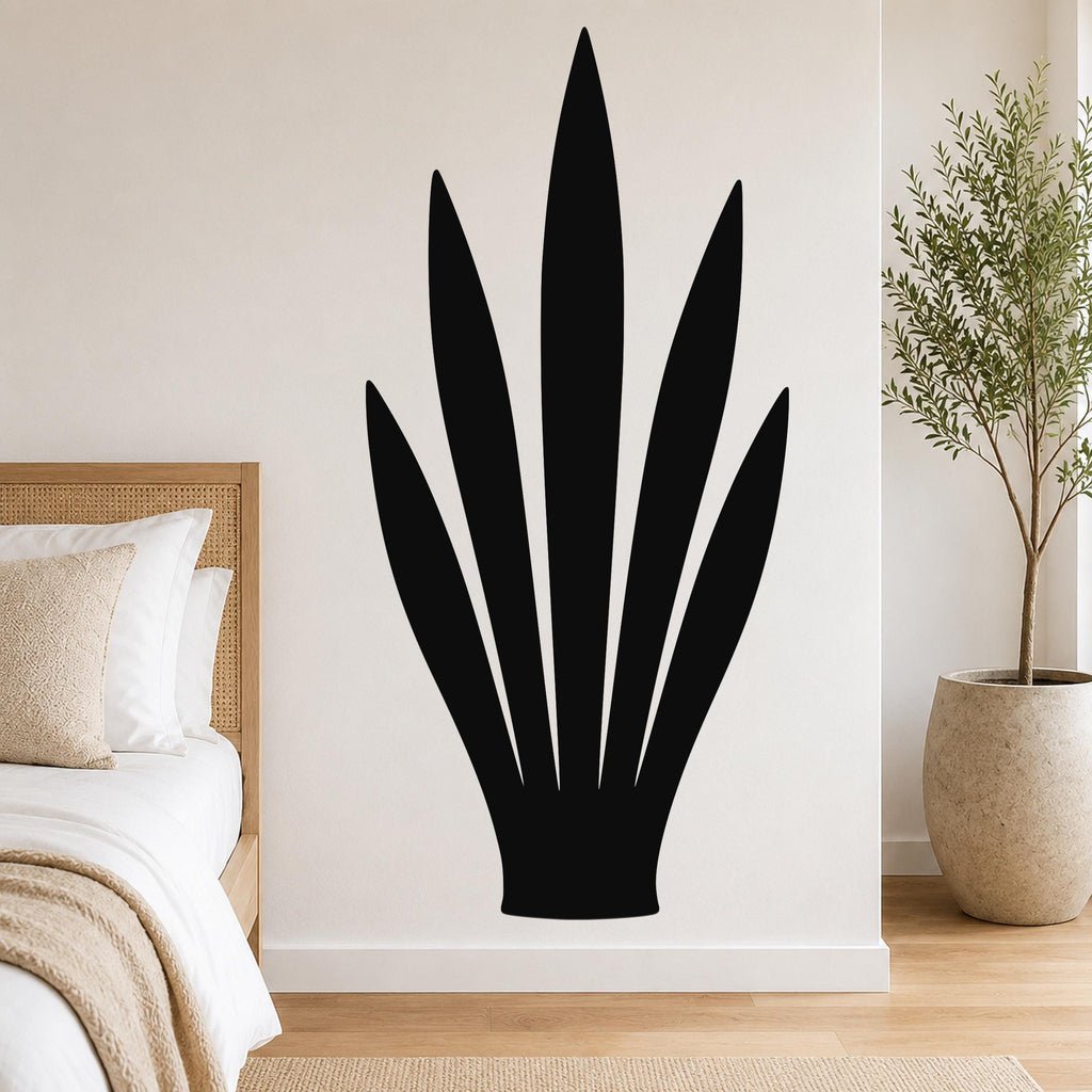 Black metal wall art in the silhouette of a snake plant, mounted on a white bedroom wall above a bed.