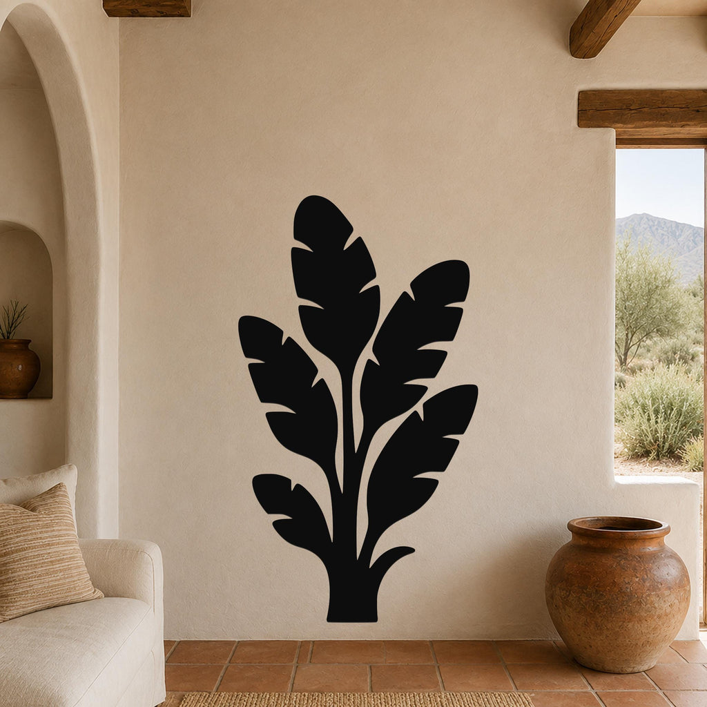 Black metal wall art featuring a tropical leaf silhouette, mounted on a beige living room wall above a sofa.