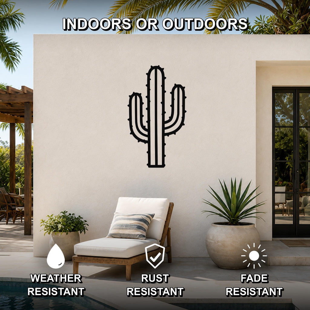 Black metal saguaro cactus wall art with spines and arms, mounted on an outdoor patio wall above a lounge chair.