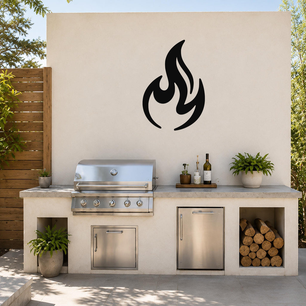 Black metal flame silhouette wall art mounted on a light-colored outdoor wall above a stainless steel grill and countertop.