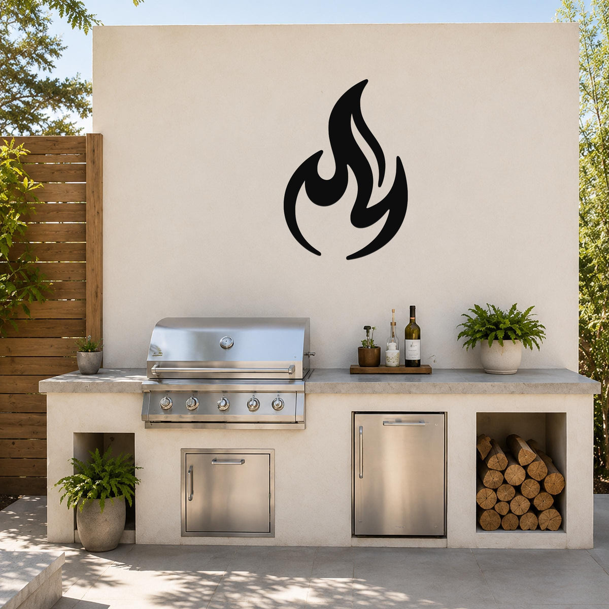 Black metal flame silhouette wall art mounted on a light-colored outdoor wall above a stainless steel grill and countertop.