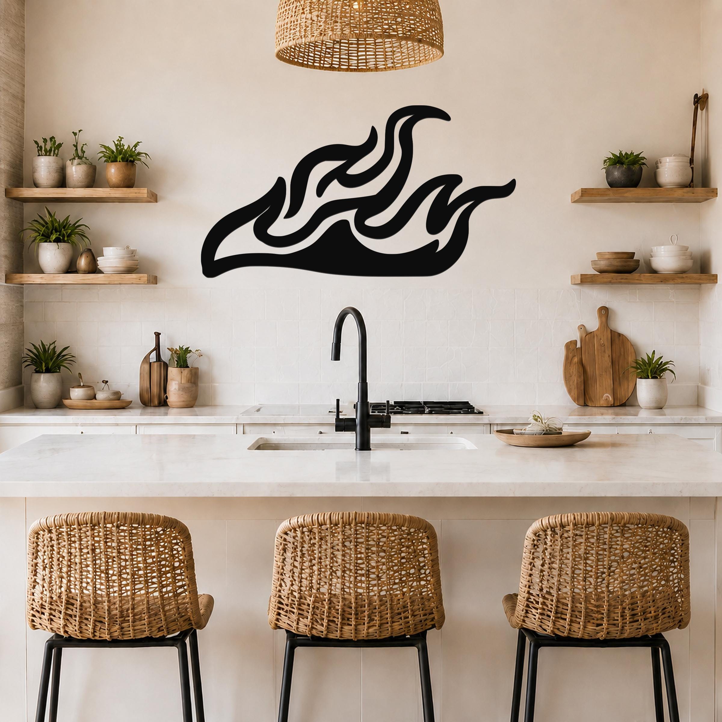 Black metal flame wall art with flowing silhouette cutouts, mounted above a kitchen counter with a sink and wicker bar stools.