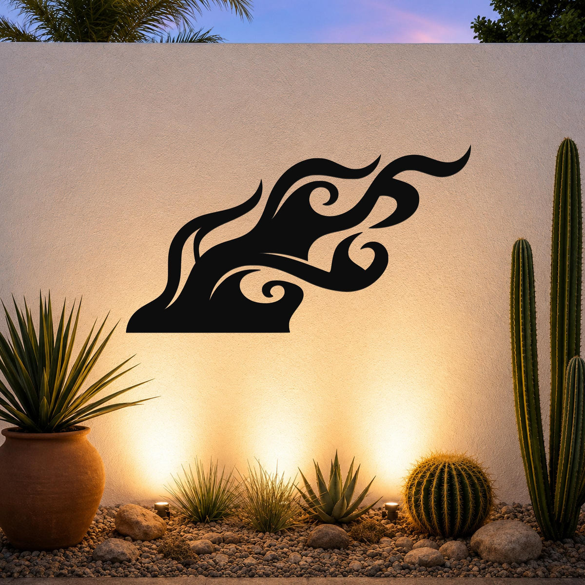 Black metal wall art with a bold, flowing flame silhouette, mounted on an outdoor wall above a desert garden with cacti and warm uplighting.
