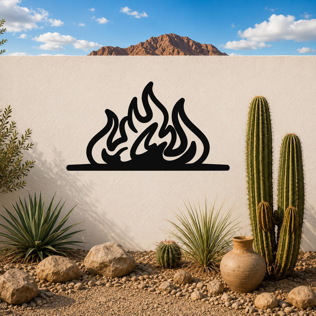 Black metal flame silhouette wall art mounted on a white outdoor wall above a desert garden with cacti and rocks.