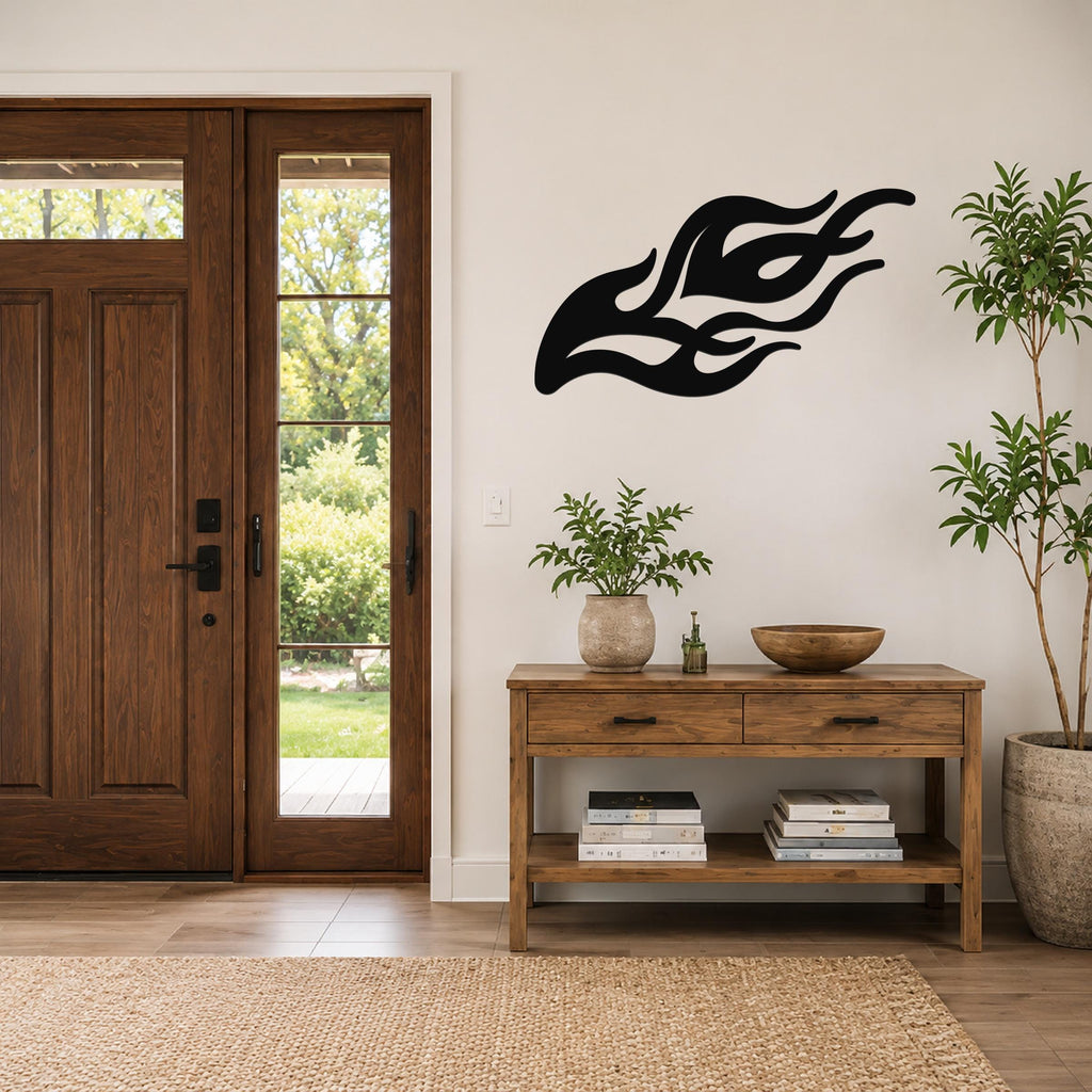 Black metal flame wall art with flowing silhouette cutouts, mounted on a white wall above a wooden console table in a modern entryway.