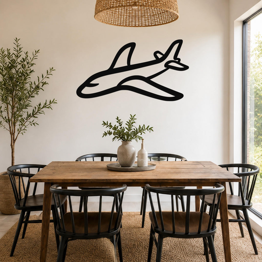 Black metal airplane wall art silhouette mounted on a white wall above a wooden dining table in a bright dining room.