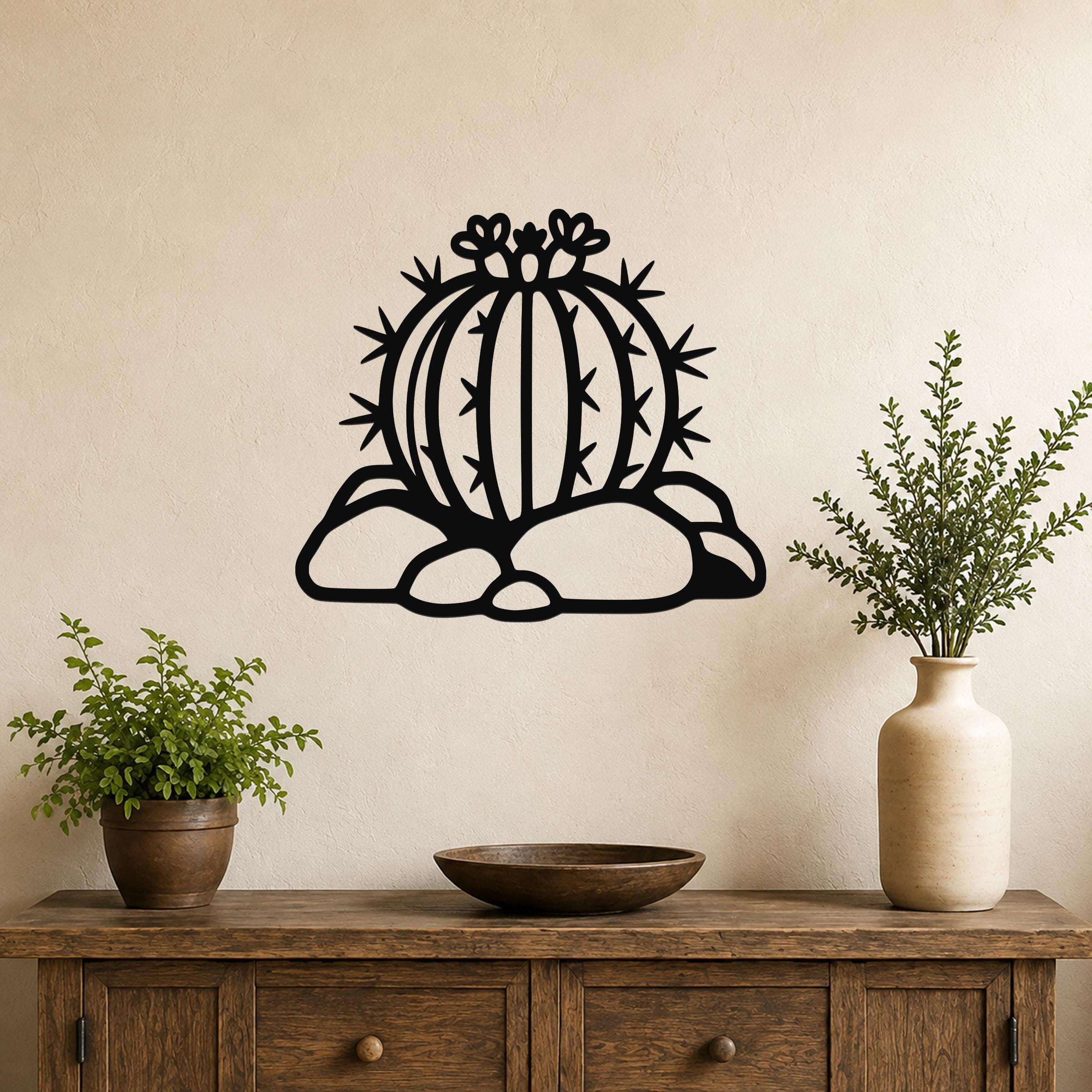 Black metal barrel cactus wall art with spines and flower cutouts, mounted on a beige wall above a wooden console table.