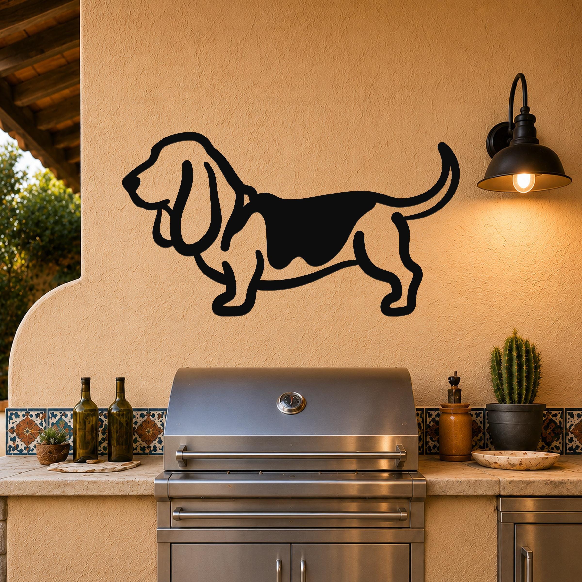 Black metal Basset Hound silhouette wall art mounted on a stucco wall above an outdoor grill, with a lit wall sconce to the right.