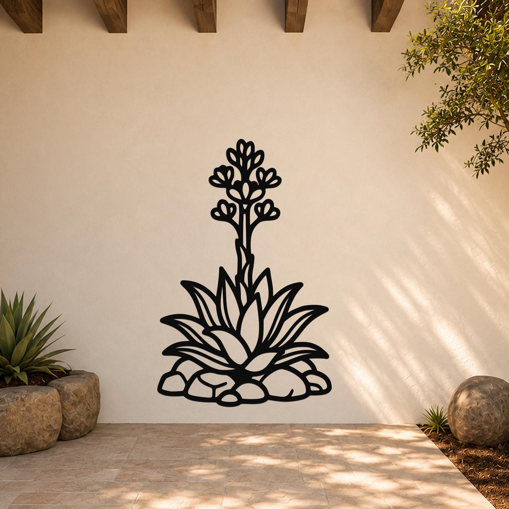 Black metal agave wall art with blooming flower and leaf cutouts, mounted on an outdoor patio wall above a tiled floor.