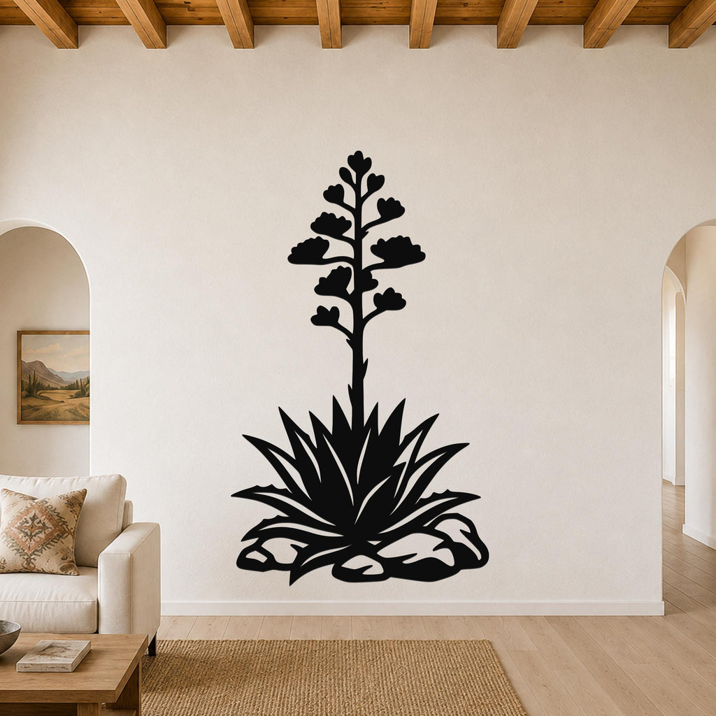 Black metal agave wall art with a tall flowering stalk and spiky rosette cutout, mounted on a living room wall above a sofa.