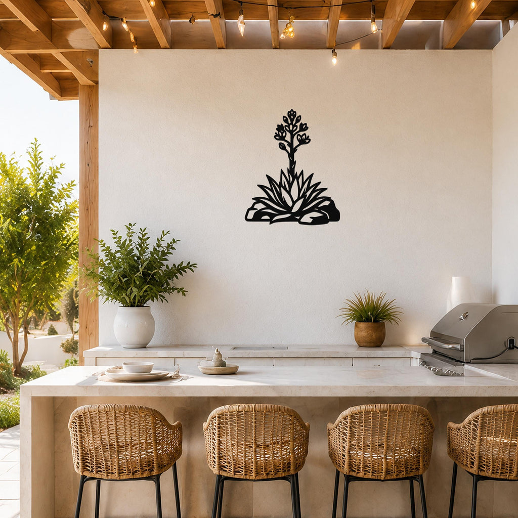 Black metal agave wall art with blooming flower cutout, mounted on a white outdoor kitchen wall above a counter.