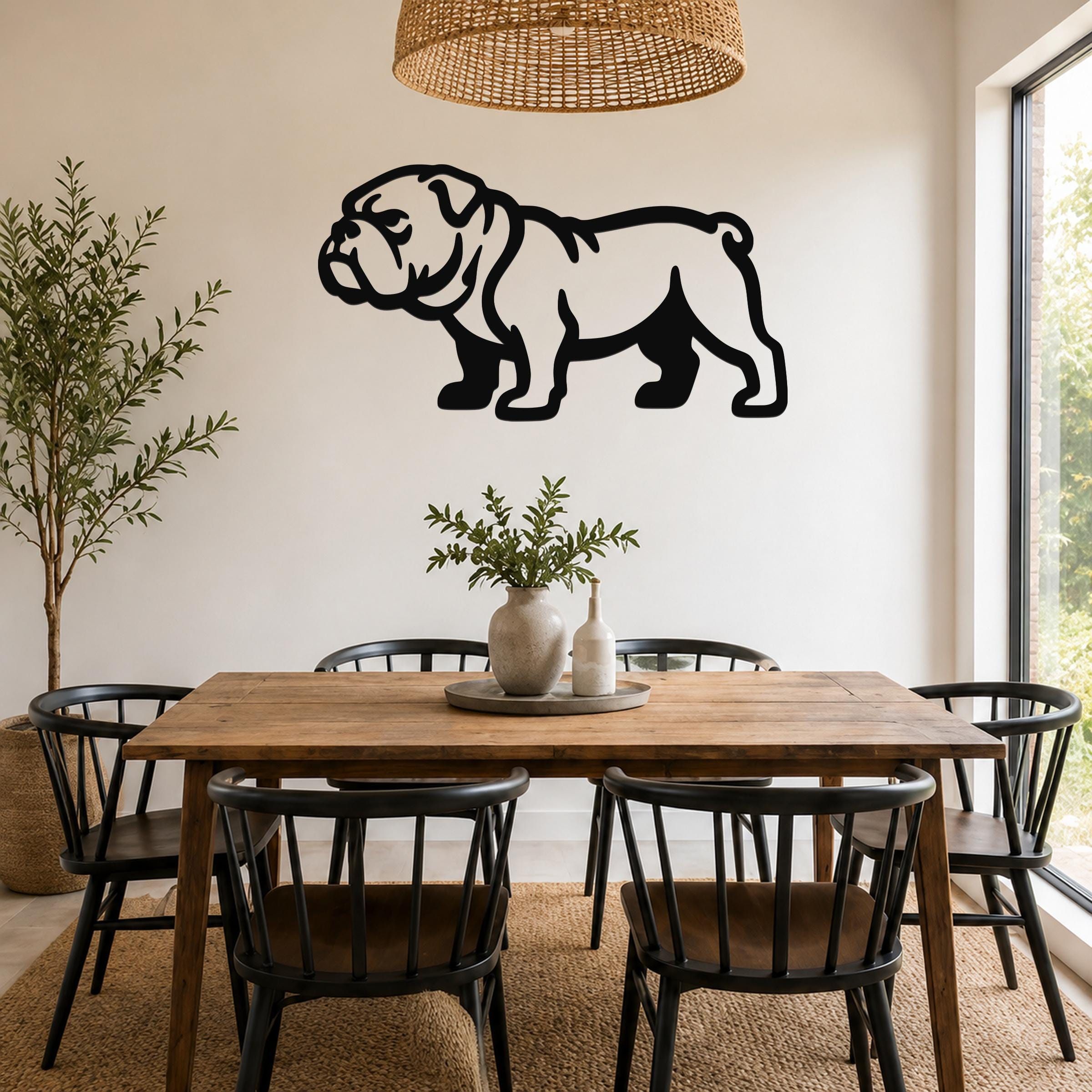 Black metal bulldog wall art silhouette mounted on a white wall above a wooden dining table in a bright room.
