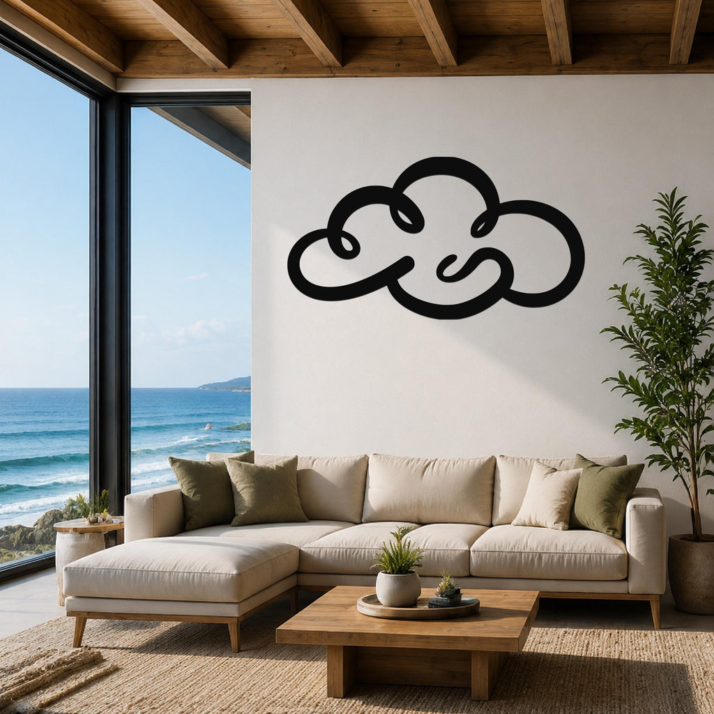 Black metal cloud wall art with flowing cutout lines, mounted above a beige sectional sofa in a living room with ocean views.