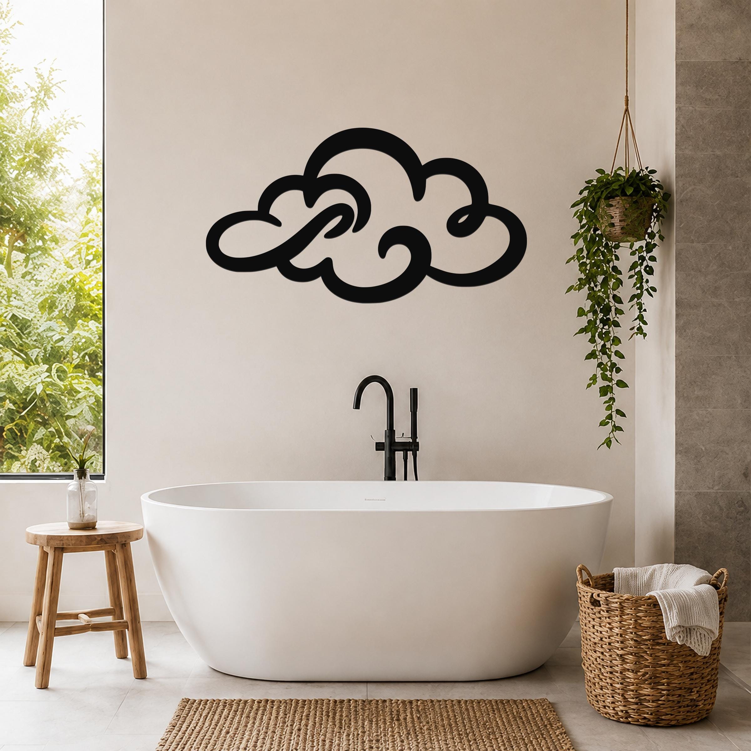 Black metal cloud wall art with flowing silhouette cutouts, mounted above a freestanding bathtub in a bright bathroom.