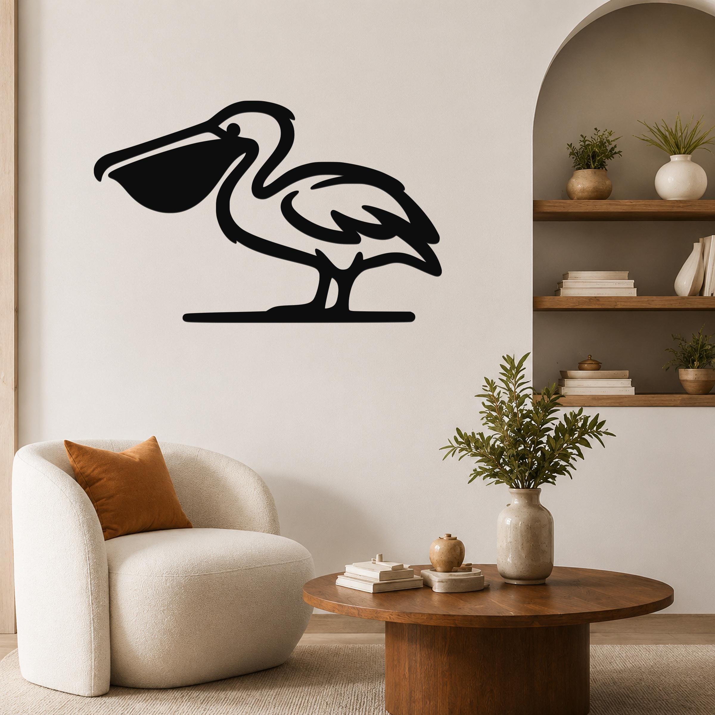 Black metal pelican wall art in silhouette style, mounted on a living room wall above a round wooden coffee table.
