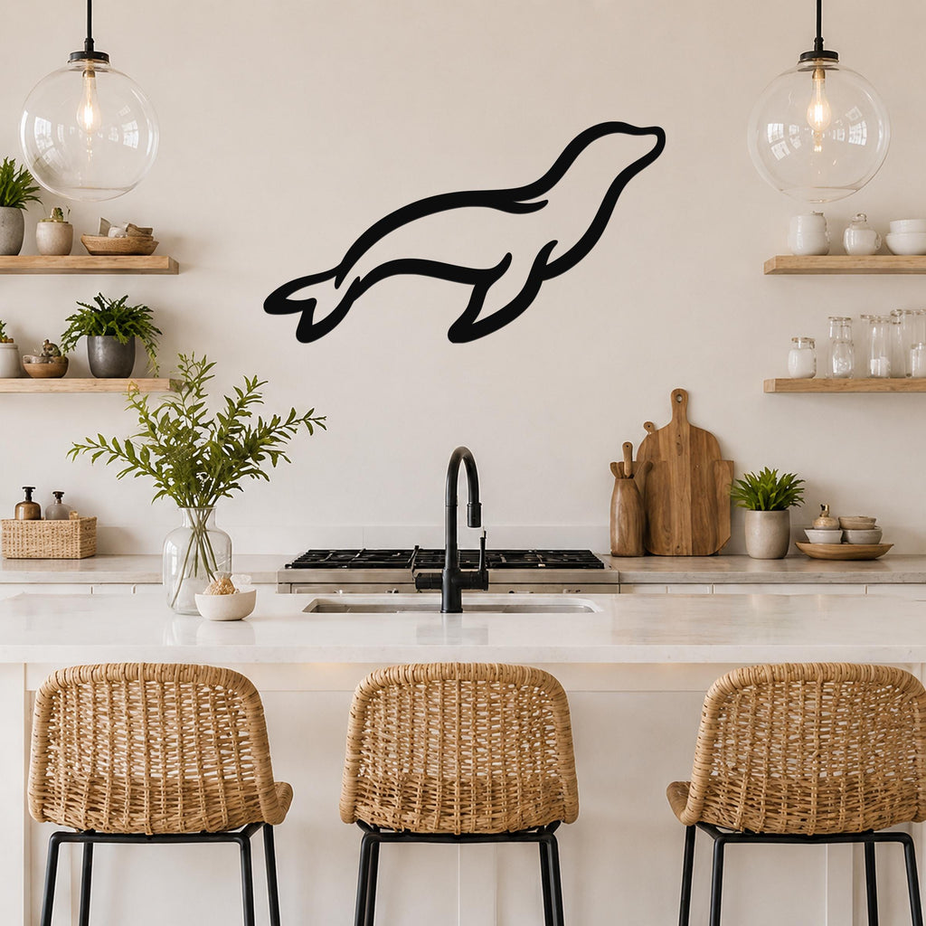 Black metal sea lion wall art with a sleek silhouette, mounted on a kitchen wall above a counter with wicker bar stools.