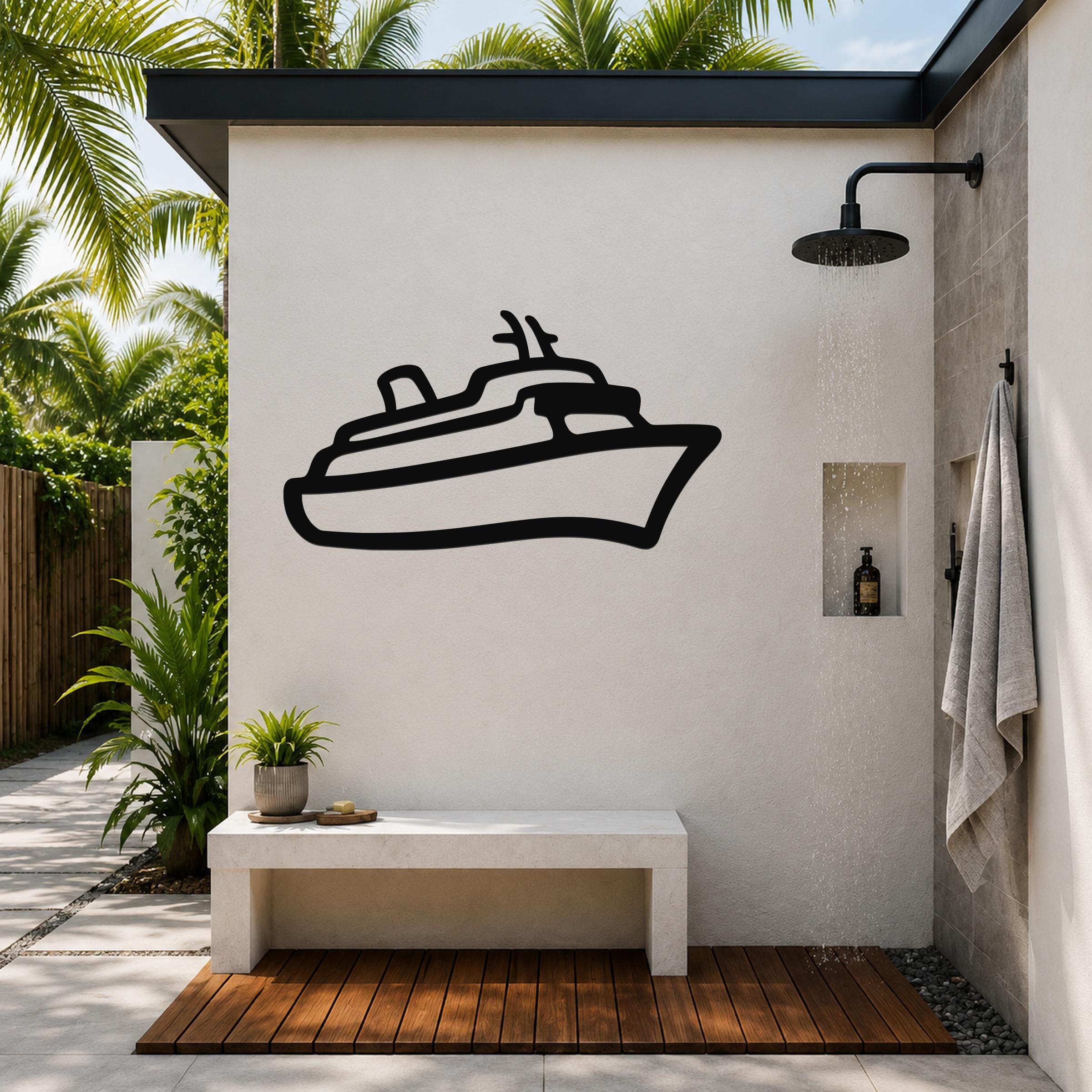 Black metal cruise ship wall art silhouette mounted on a white outdoor shower wall, above a concrete bench in a tropical patio setting.