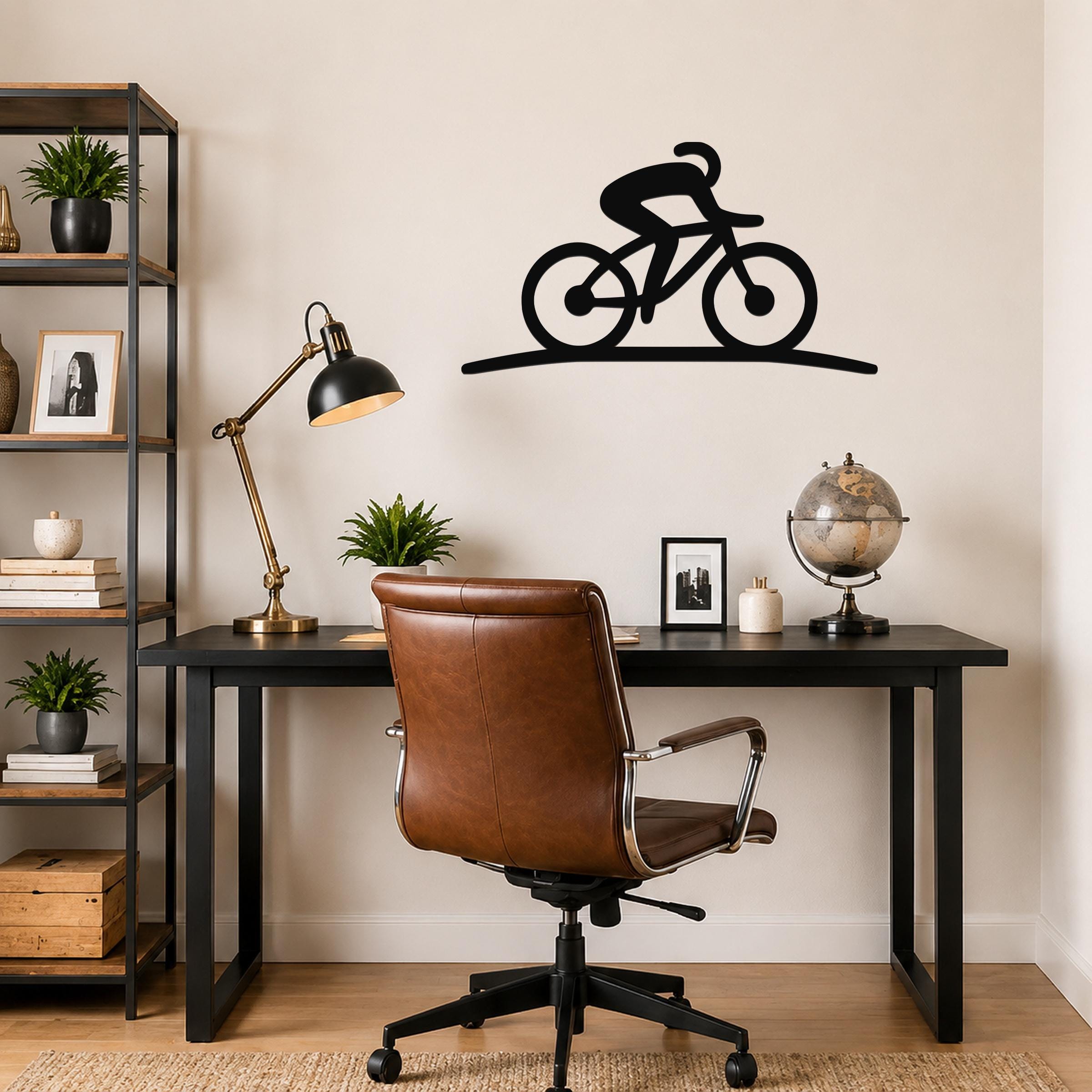Black metal wall art silhouette of a cyclist on a bike, mounted above a black desk in a home office.