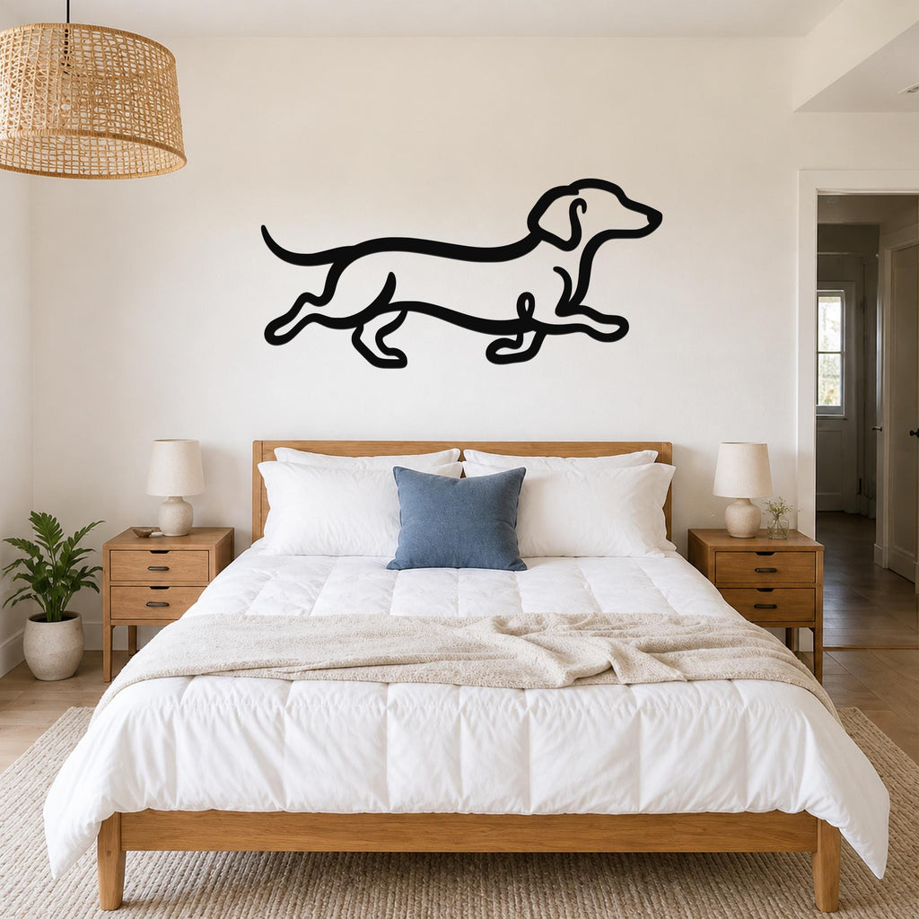 Black metal dachshund wall art in a running silhouette, mounted above a bed in a bedroom with wooden furniture and a woven pendant light.