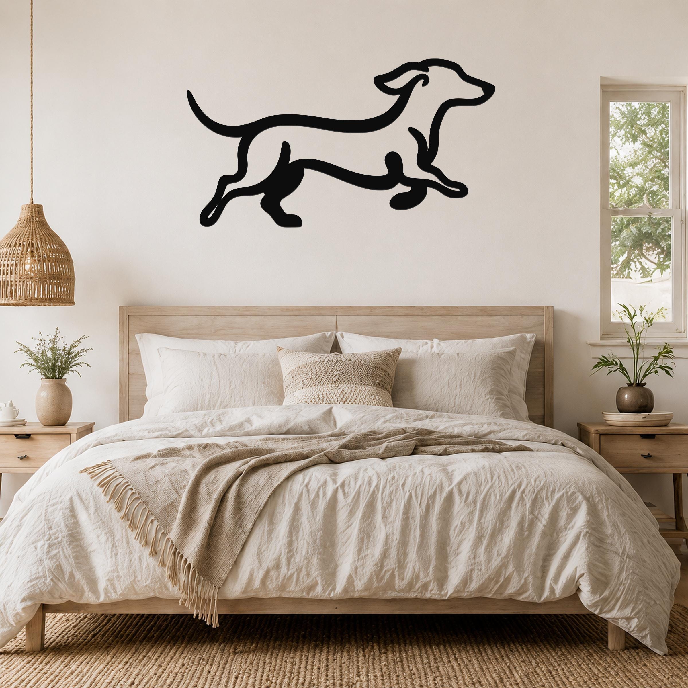 Black metal dachshund wall art in a running silhouette, mounted above a wooden bed in a neutral bedroom.
