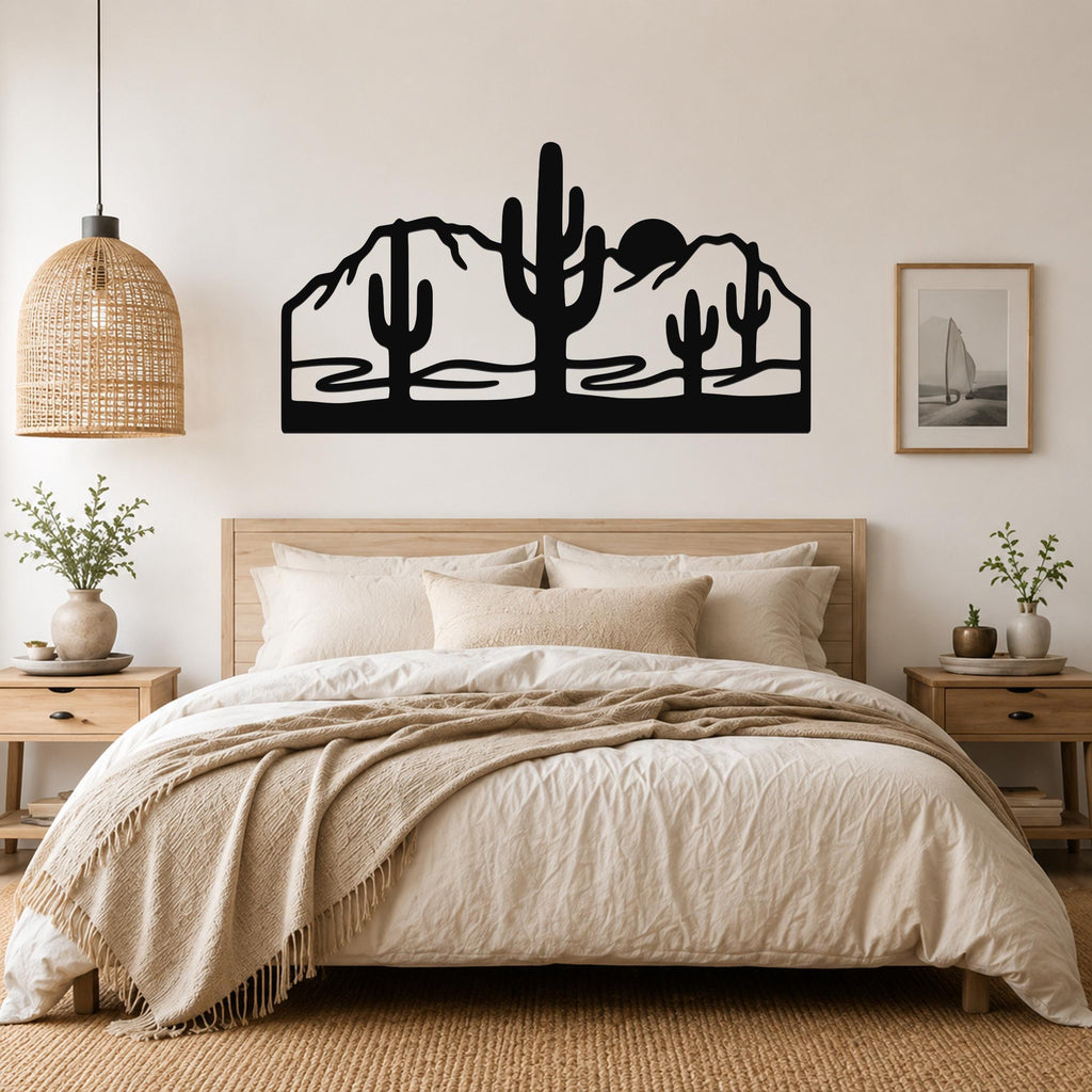 Black metal wall art with a desert silhouette of saguaro cacti and mountains, mounted above a bed in a bedroom.