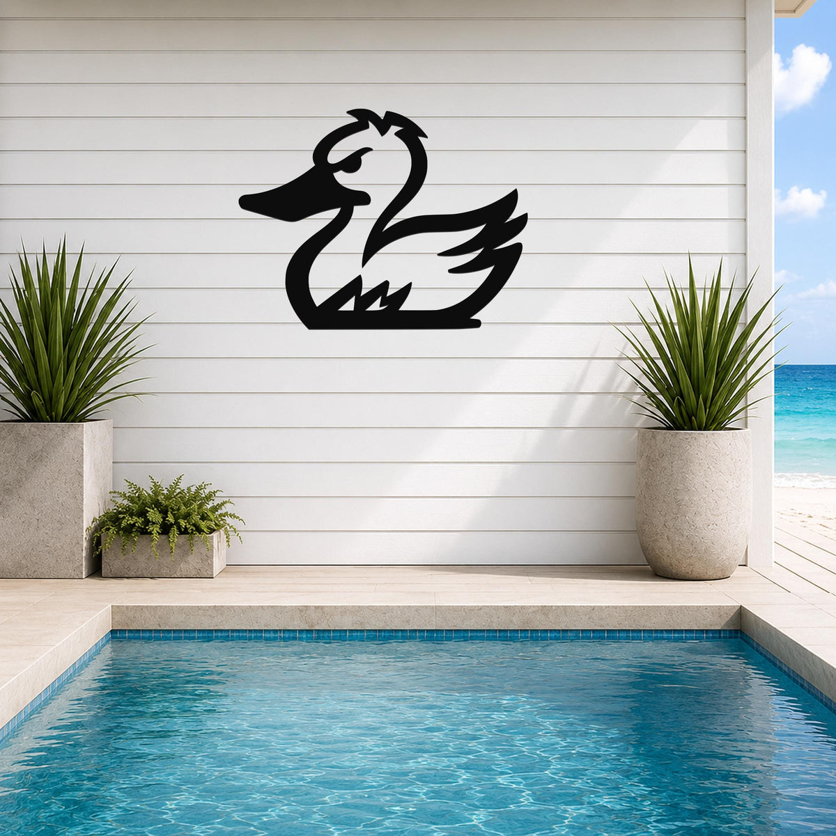 Black metal duck silhouette wall art mounted on a white horizontal siding wall above a pool, flanked by two potted plants with a beach view in the background.