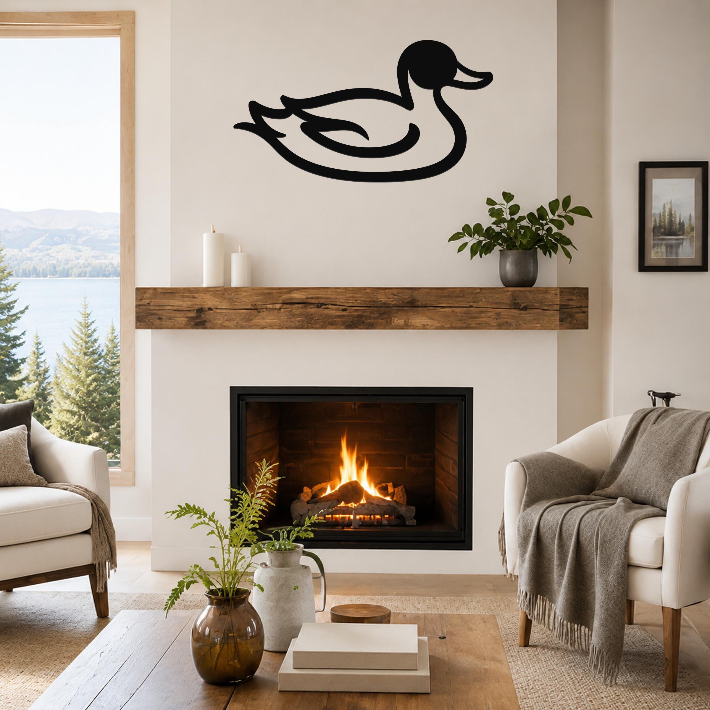 Black metal duck wall art silhouette mounted above a fireplace in a living room with a lake view.