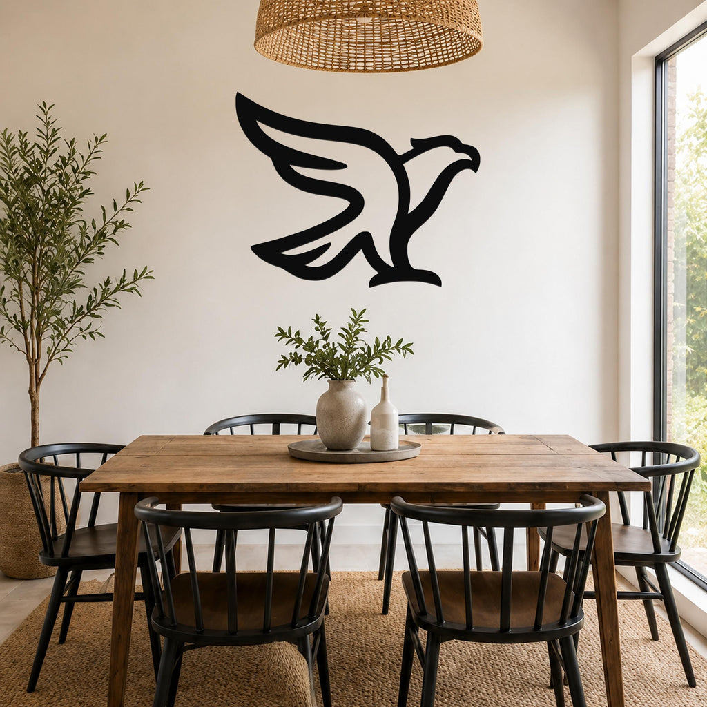 Black metal eagle wall art with a bold silhouette design, mounted on a wall above a wooden dining table in a bright, modern dining room.