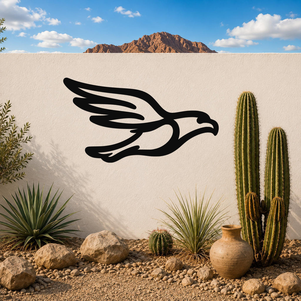 Black metal eagle wall art with a bold silhouette design, mounted on a white outdoor wall above a desert garden with cacti and rocks.