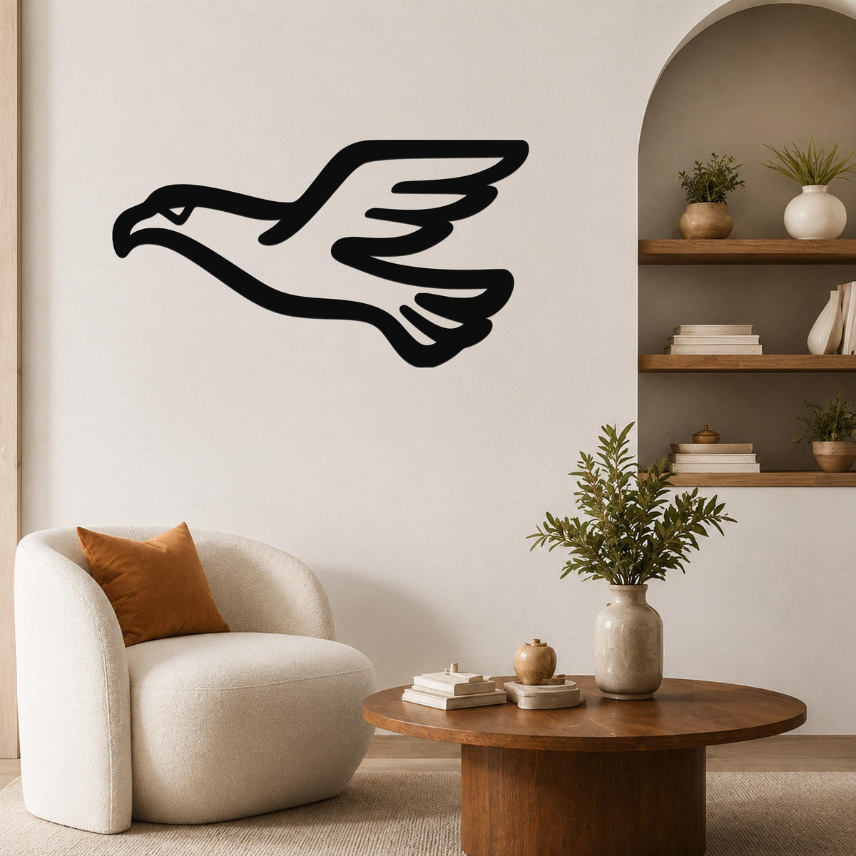 Black metal eagle wall art with a soaring silhouette, mounted on a living room wall above a white armchair.