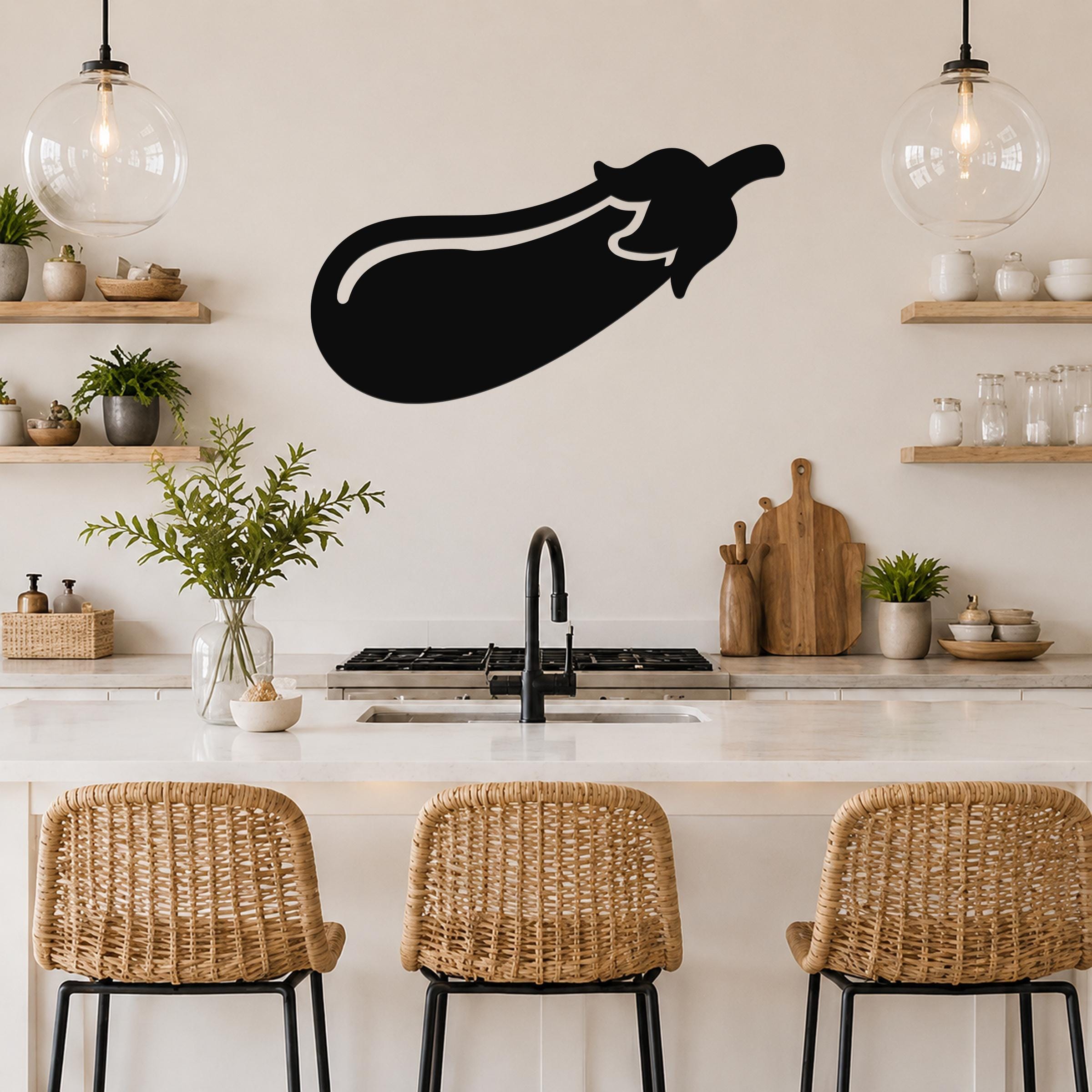 Black metal eggplant wall sculpture with a white outline, mounted on a kitchen wall above a counter with wicker bar stools.