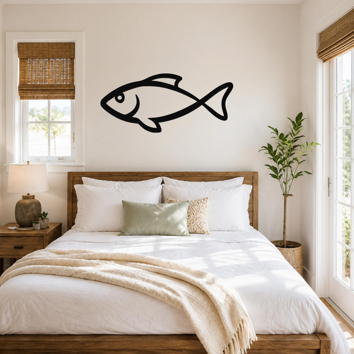 Black metal fish wall art silhouette mounted above a wooden bed in a bright bedroom with white bedding and natural light.
