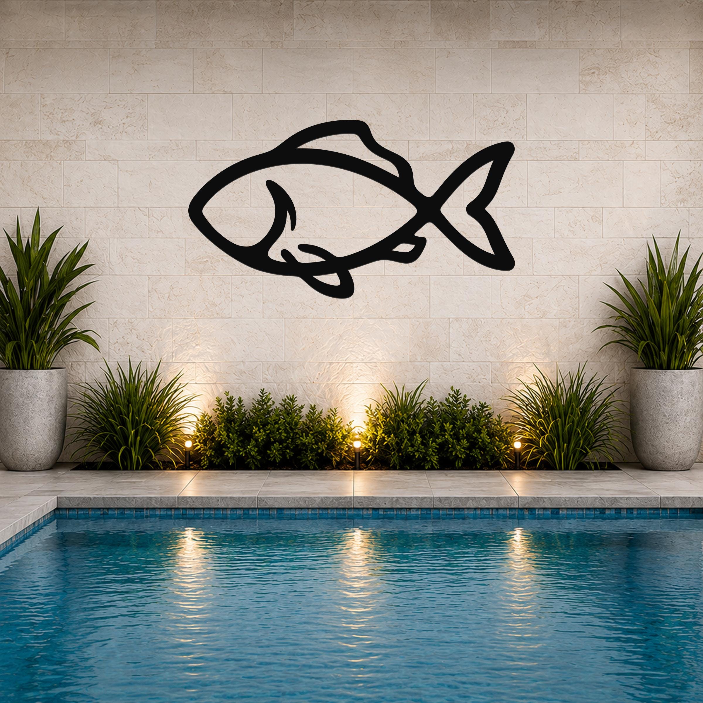 Black metal fish wall art with bold silhouette lines, mounted on a tiled wall above a pool with potted plants and ground lights.