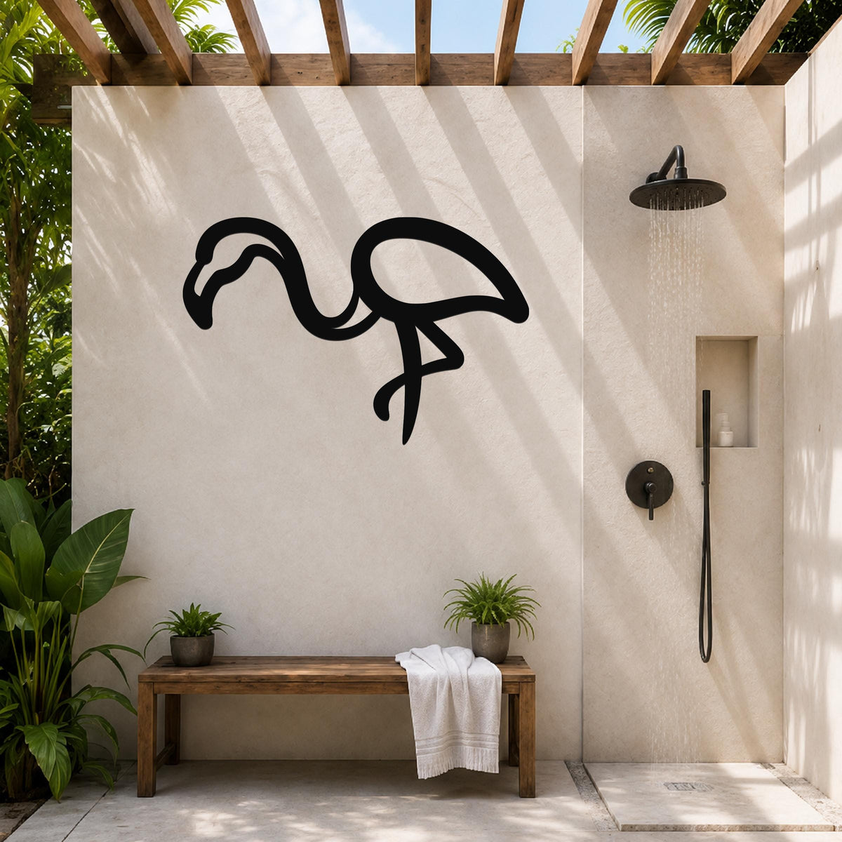 Black metal flamingo wall art silhouette mounted on a beige outdoor shower wall, above a wooden bench with potted plants.