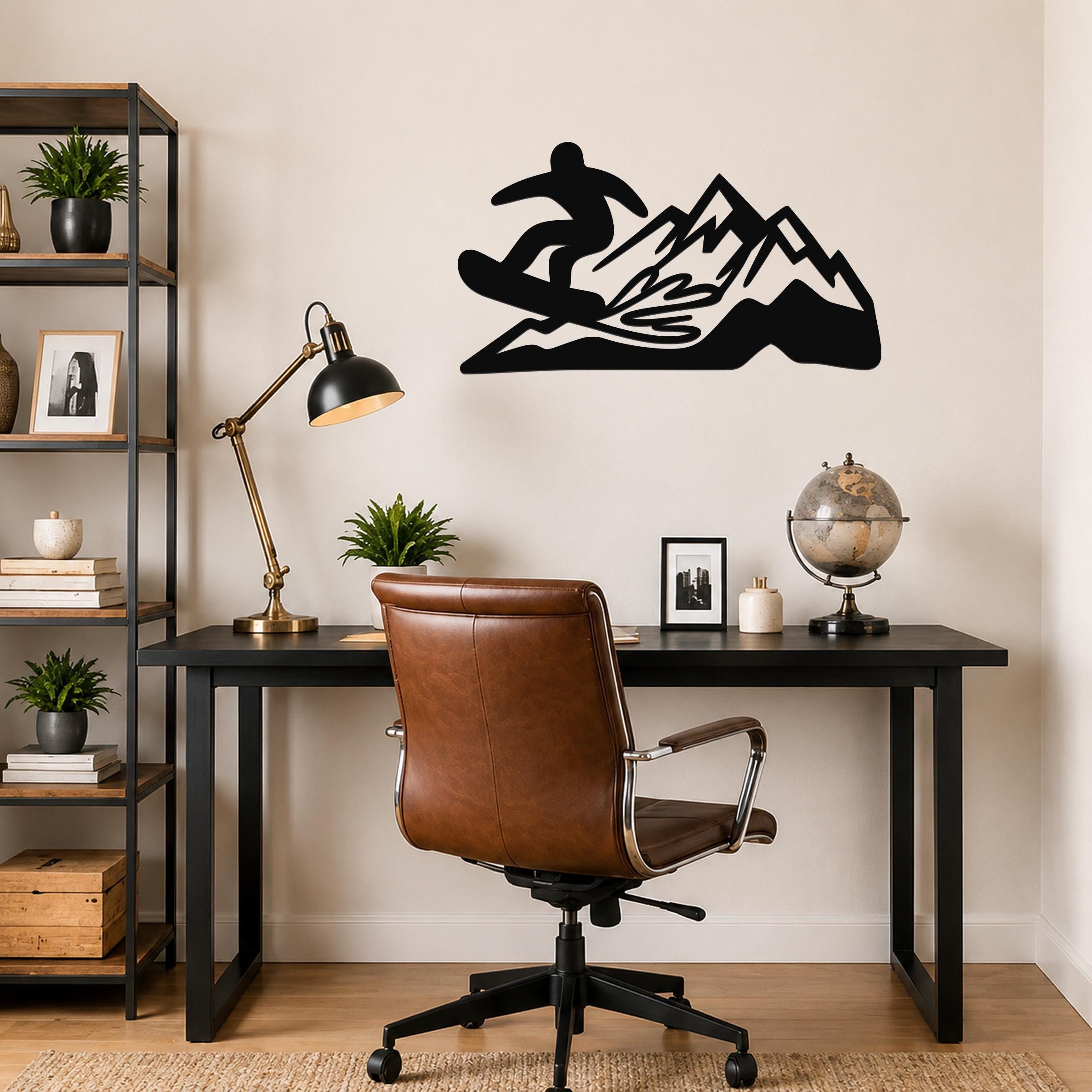 Black metal wall art featuring a snowboarder silhouette above a mountain range, mounted on a wall above a desk in a home office.