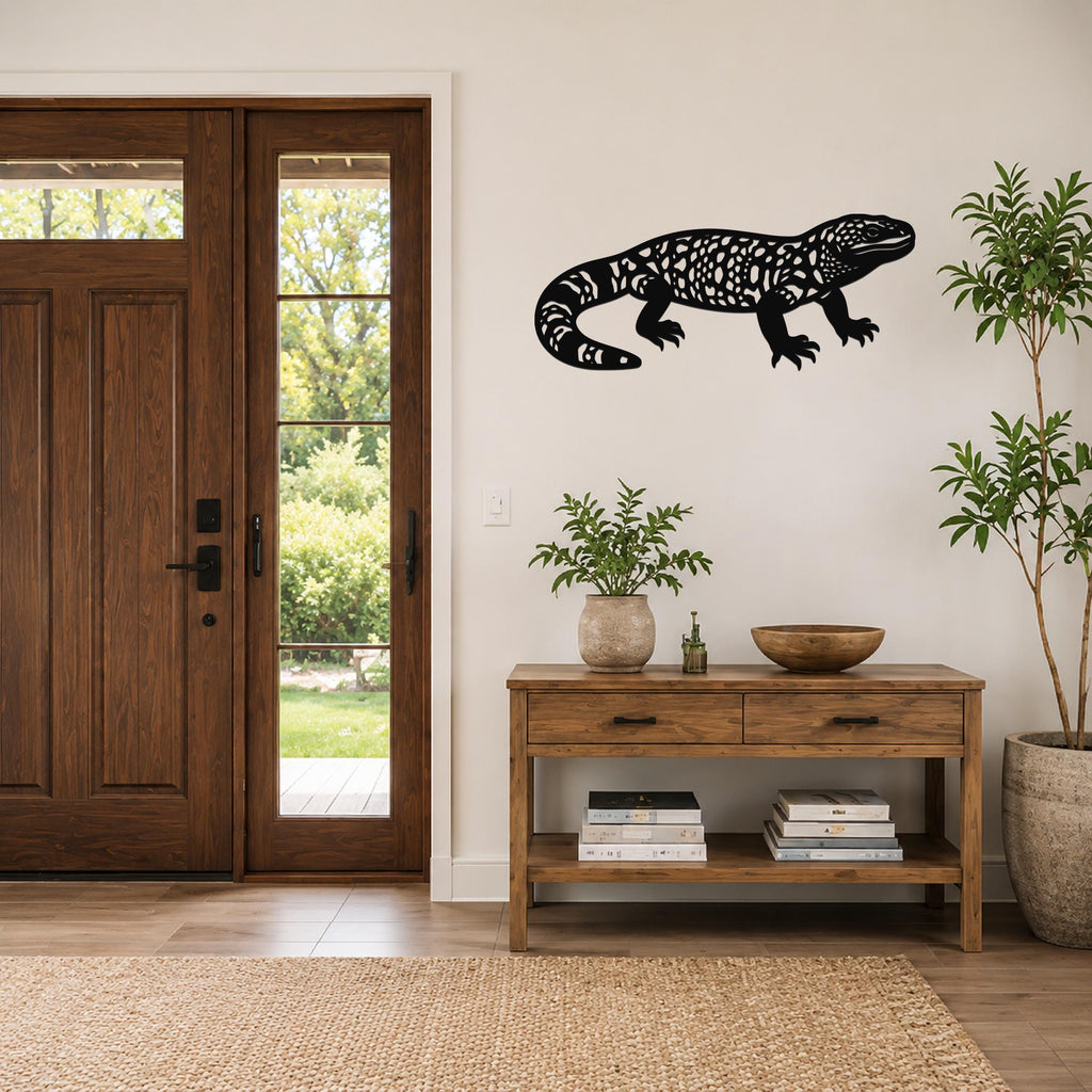 Black metal Gila monster wall art with intricate cutout patterns, mounted on a light-colored wall above a wooden console table in a entryway.