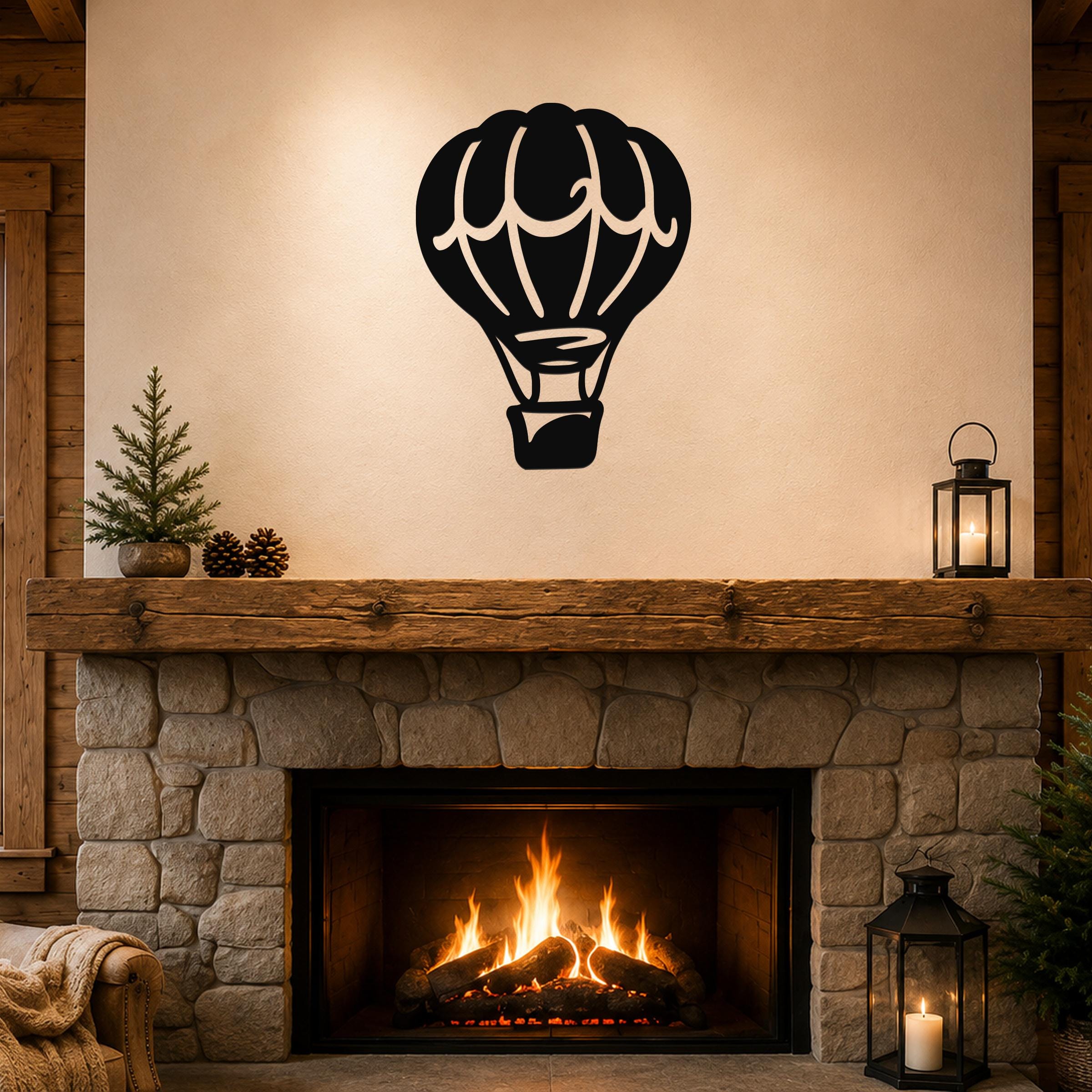 Black metal hot air balloon wall art with internal basket and panel cutouts, mounted above a stone fireplace in a rustic living room.