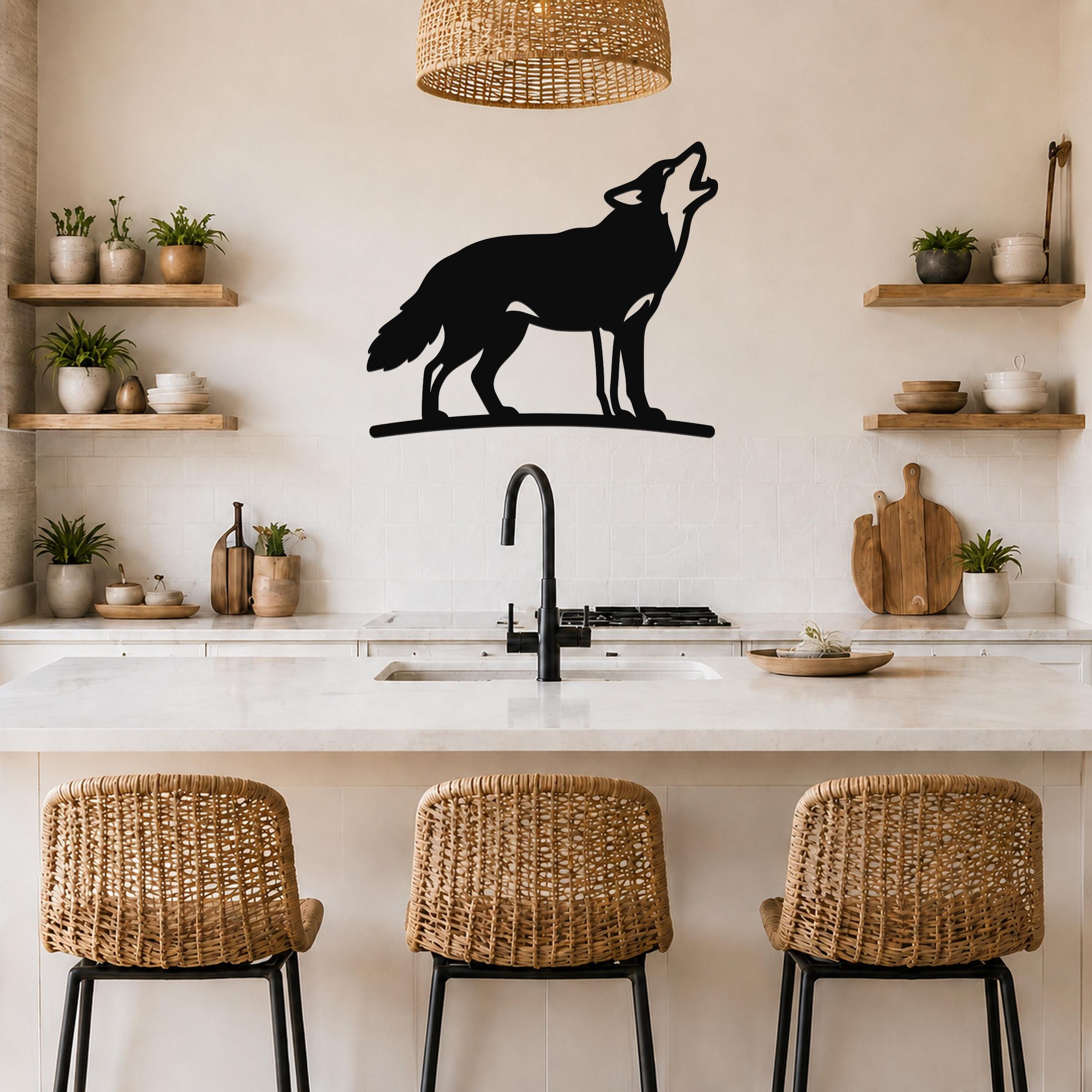 Black metal coyote wall art in a howling silhouette, mounted above a kitchen counter with a sink and wicker bar stools.