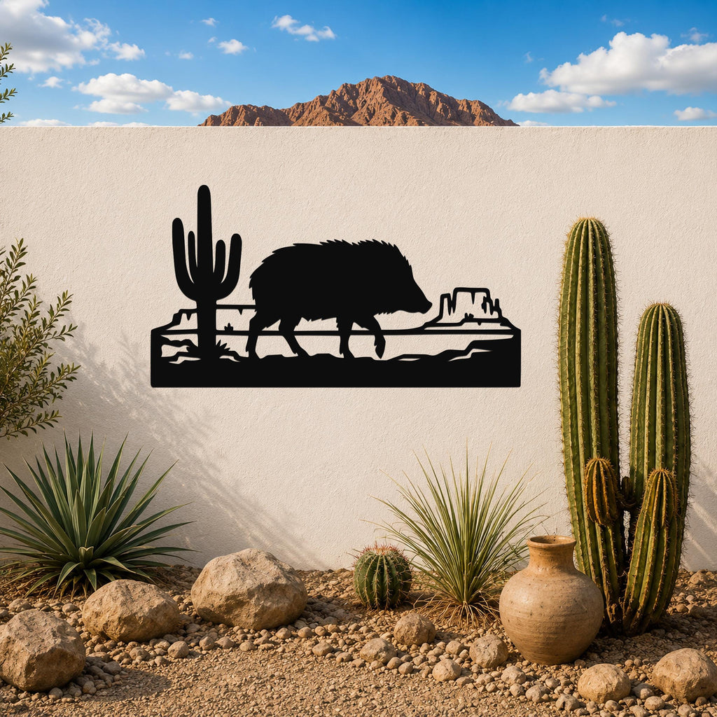 Black metal wall art silhouette of a javelina walking past a saguaro cactus and canyon rock formation, mounted on an outdoor wall above a desert garden.