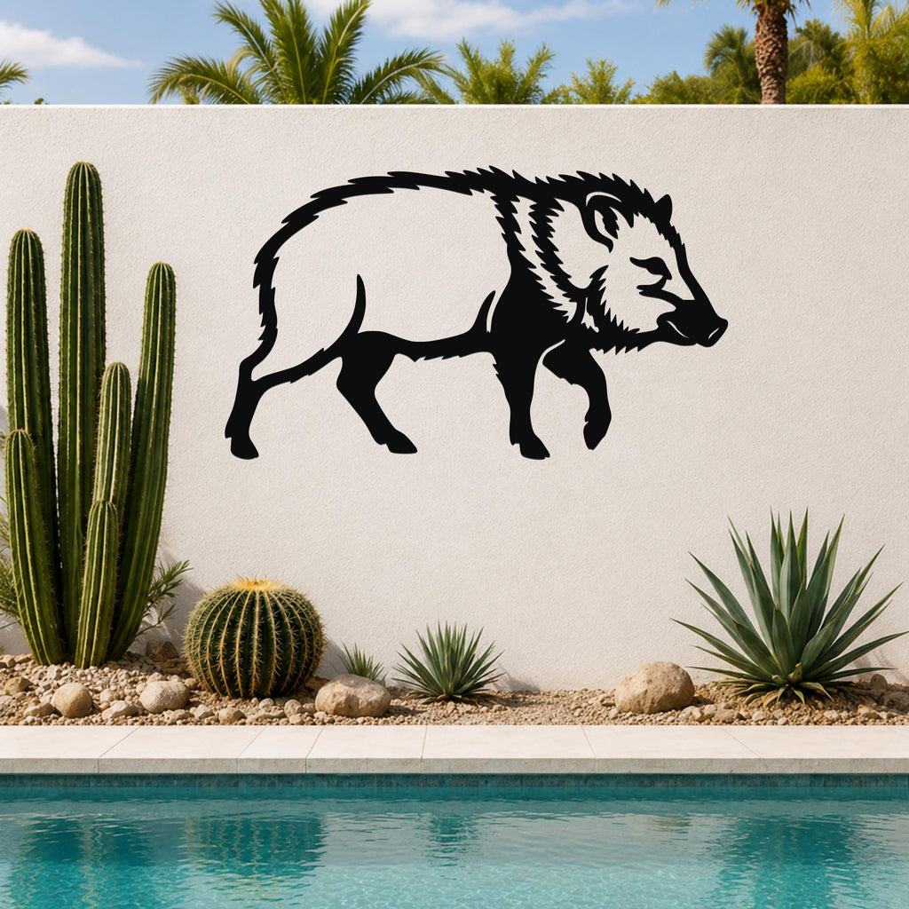 Black metal javelina wall art silhouette mounted on a white outdoor wall above a pool, with cacti and desert plants in the foreground.
