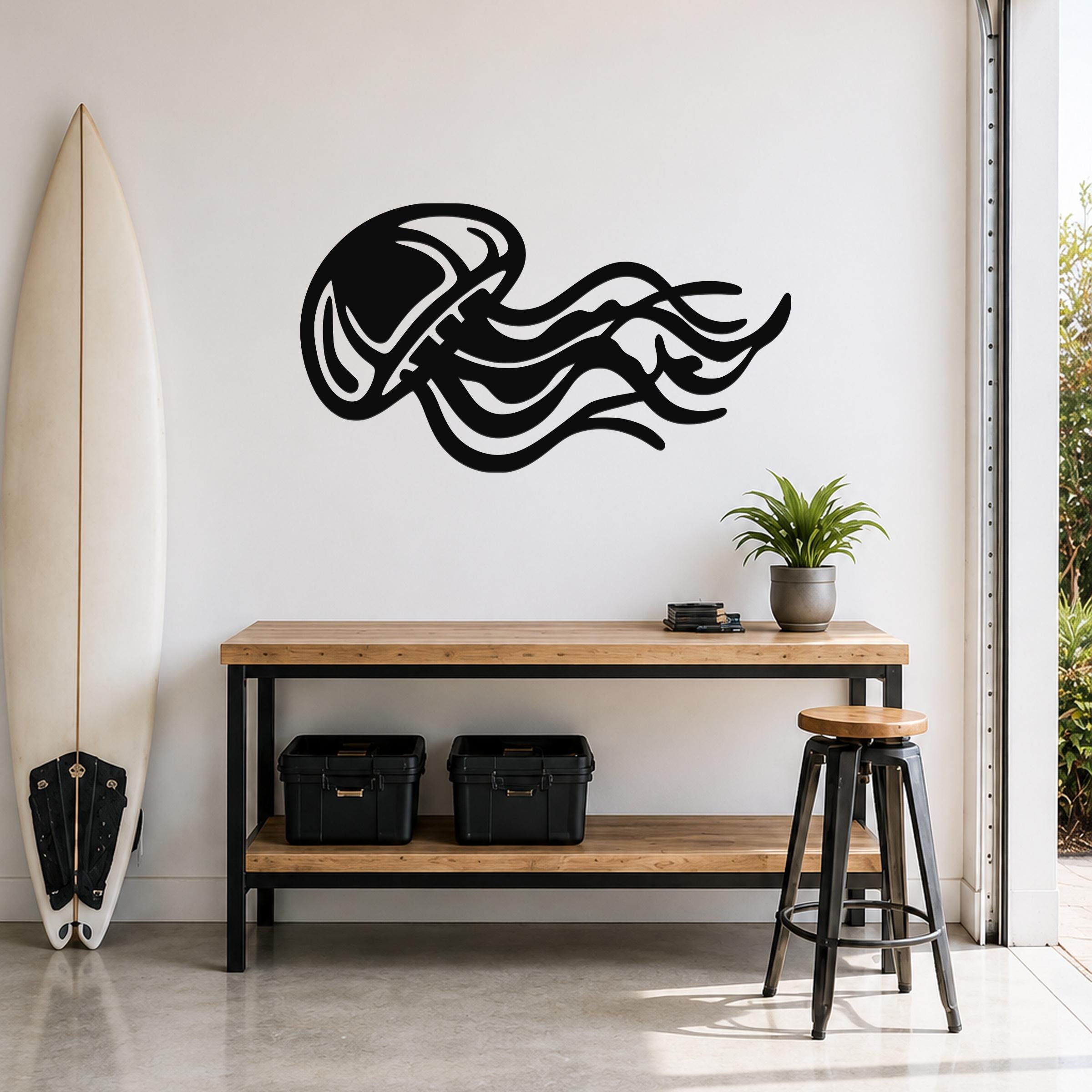 Black metal jellyfish wall art with flowing tentacle cutouts, mounted on a white wall above a wooden console table in a modern entryway.
