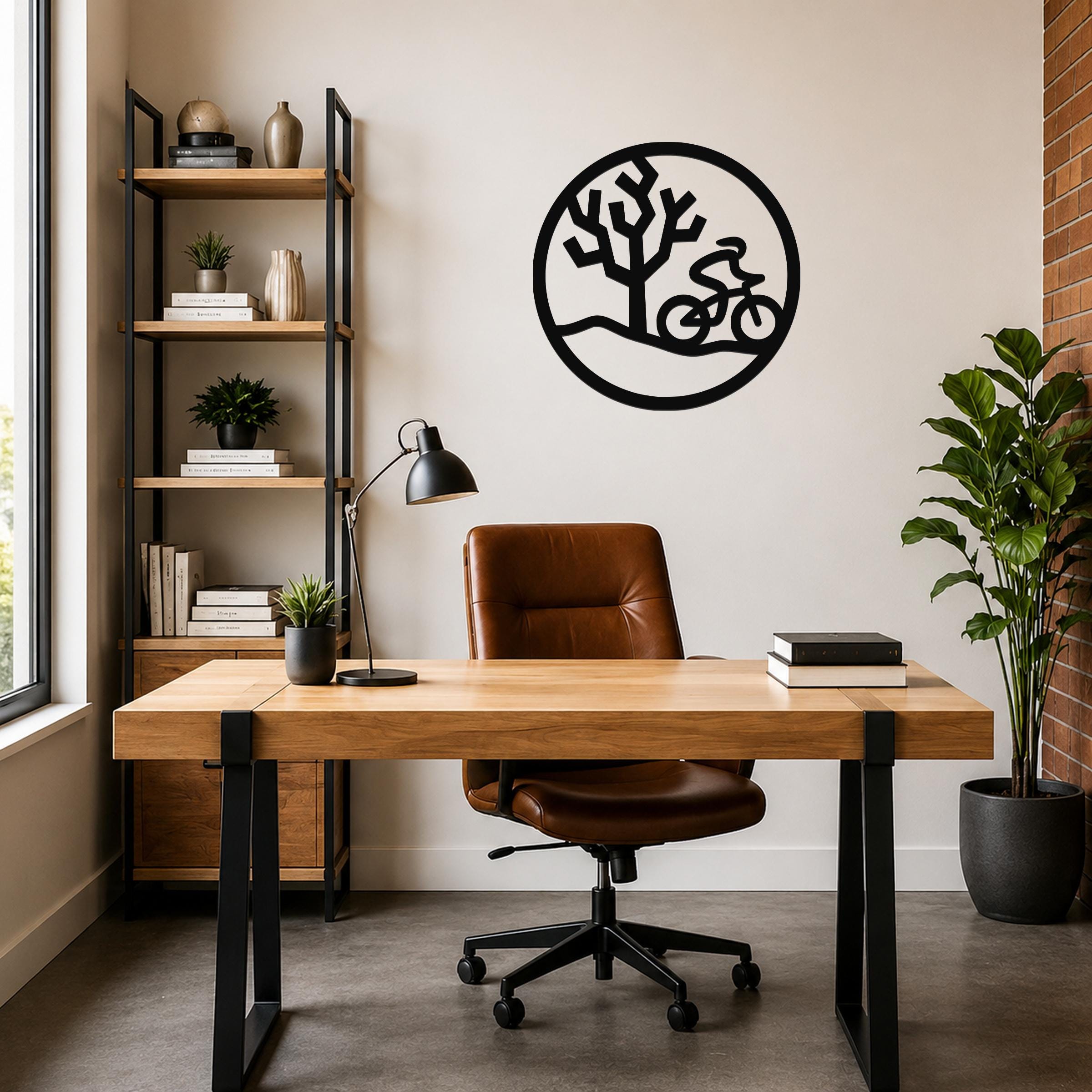 Black metal wall art with a circular silhouette of a cyclist and a Joshua tree, mounted on a wall above a wooden desk in a home office.