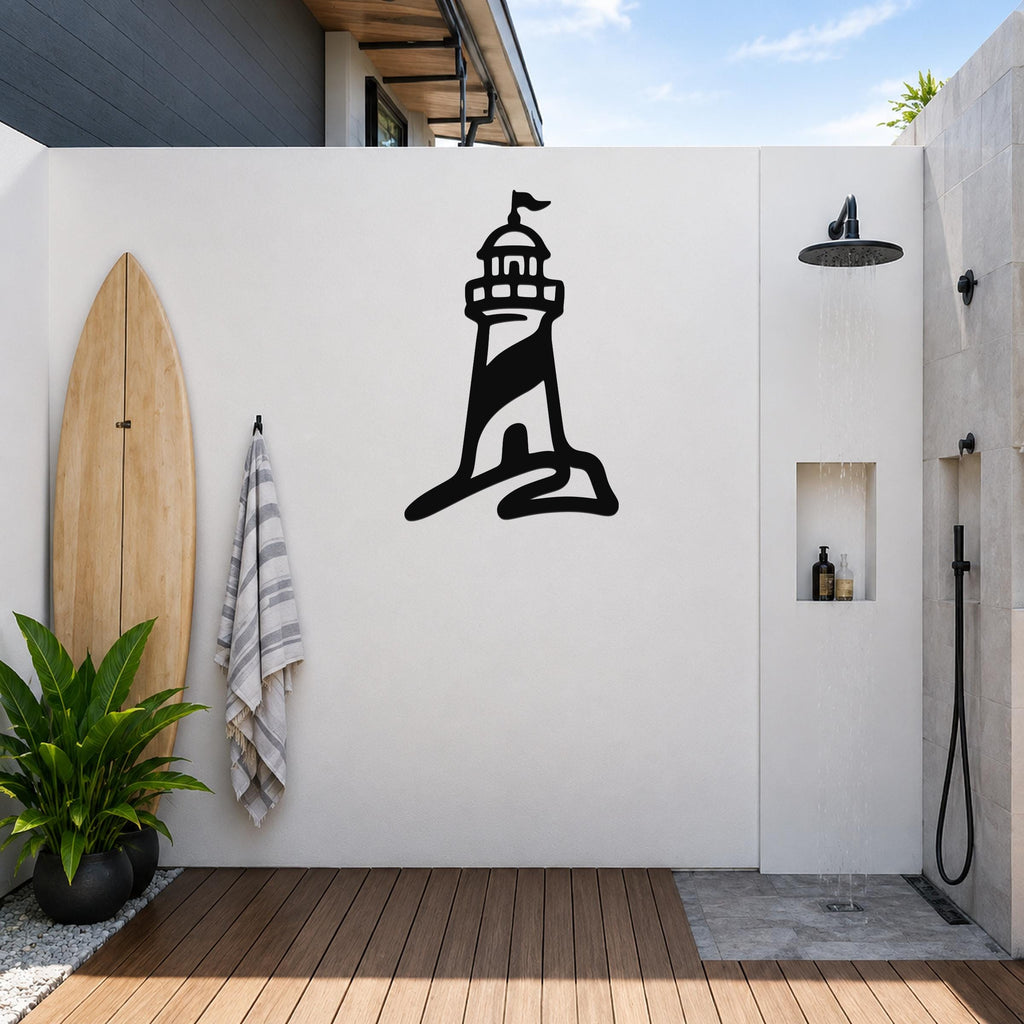 Black metal lighthouse wall art with a silhouette design, mounted on a white outdoor wall above a wooden deck near a shower area.
