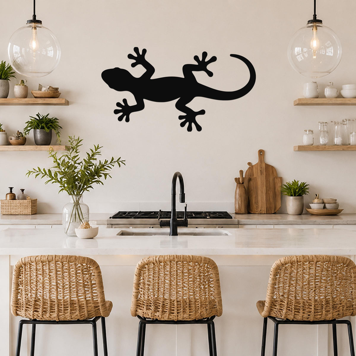 Black metal lizard wall art silhouette mounted on a kitchen wall above a counter, with visible cutout details of the gecko's limbs and tail.