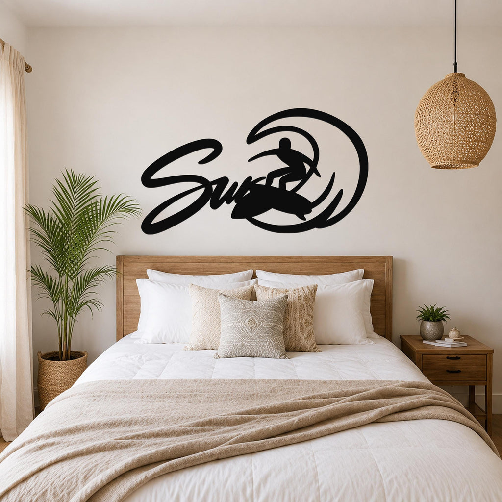 Black metal wall art featuring a surfer silhouette riding a wave, mounted above a wooden bed in a bedroom.