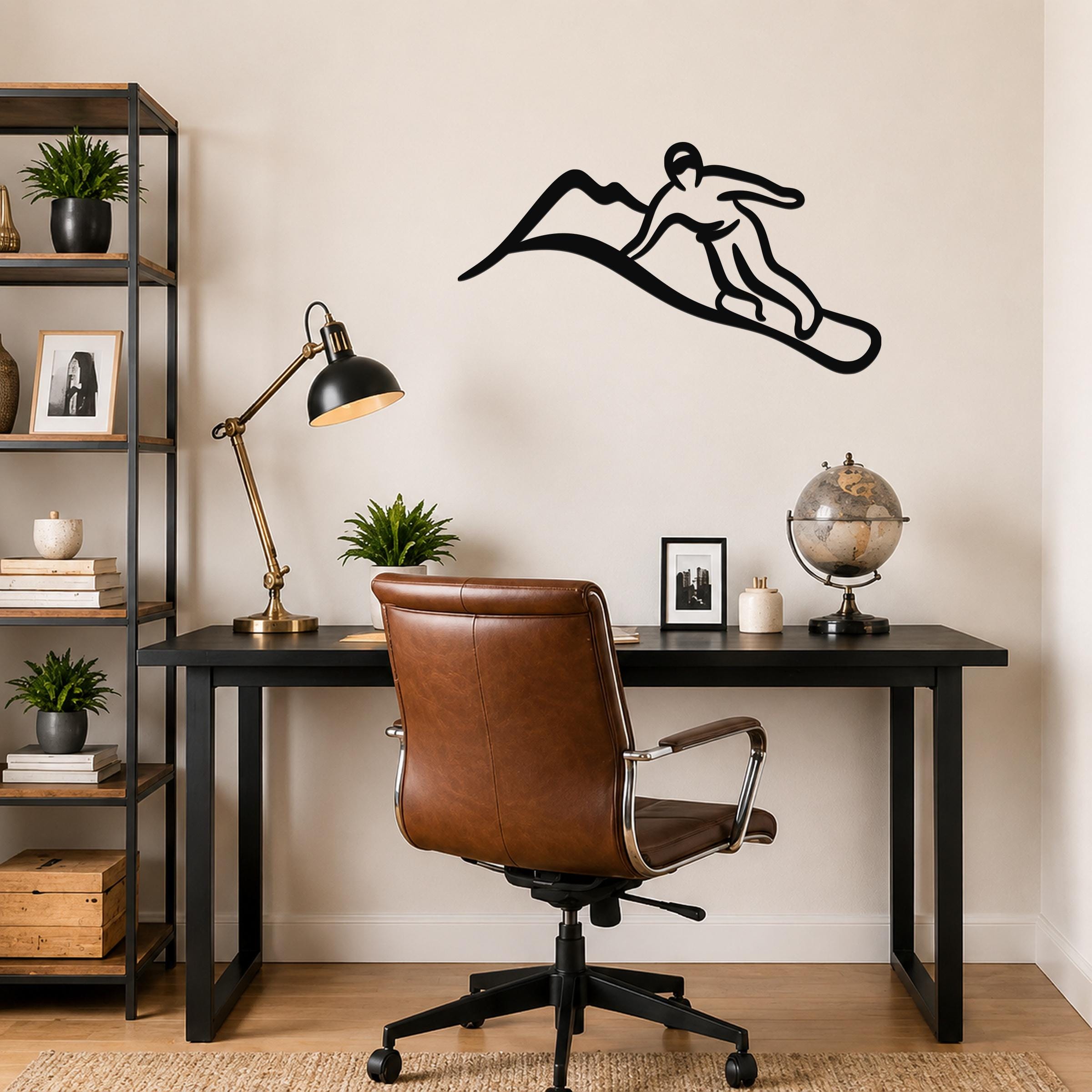 Black metal wall art silhouette of a snowboarder in motion, mounted above a black desk in a home office.